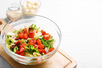 Tasty salad in glass dish on color wooden table background
