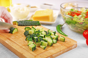 Female hands cutting vegetables for salad, at kitchen