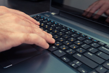 Man typing on a keyboard with letters in Hebrew and English - Laptop keyboard