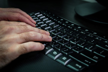 Man typing on a keyboard with letters in Hebrew and English - Wireless keyboard - Dark atmosphere