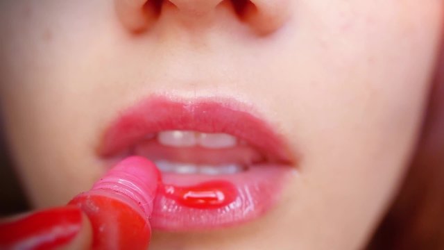 Woman paints her  sexy lips with lipstick in slowmotion. Bright red