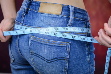 slim woman measuring body, wearing jeans