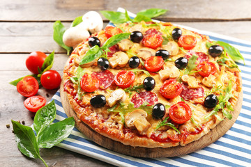 Delicious tasty pizza with ingredients on wooden table