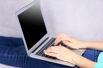 Fototapeta premium Woman sitting on sofa with a laptop in a room