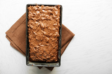 Tasty cake with nut cream in pan on white wooden table, close up