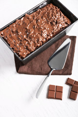 Tasty cake in pan and chocolate on white wooden table, close up