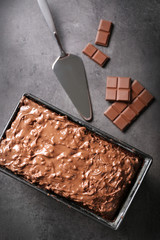 Tasty cake in pan and chocolate on grey background, close up