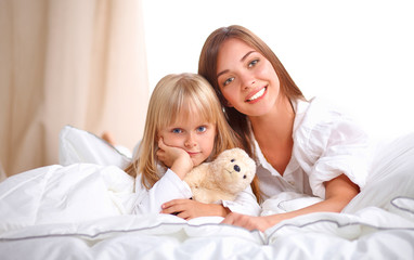 Woman and young girl lying in bed smiling