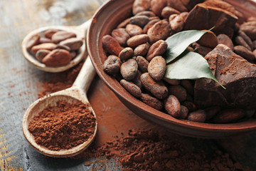 Spoon with aromatic cocoa powder and green leaf, close up