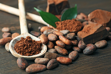 Spoon with aromatic cocoa and chocolate on wooden background, close up
