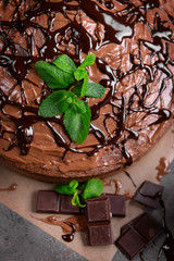 Decorated chocolate pie with mint and chocolate bar on grey table