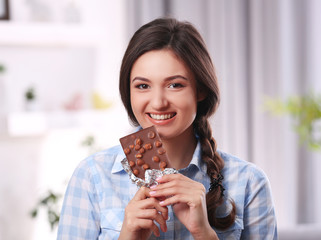 Portrait of beautiful young brunette with chocolate in the room , close up