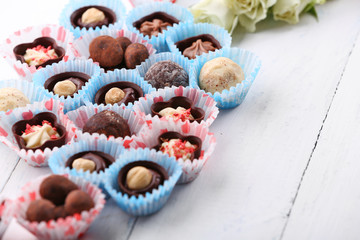 Set of chocolate candies with flowers on a light wooden background, close up