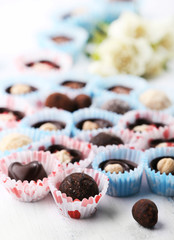Set of chocolate candies with flowers on a light wooden background, close up