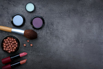 Make-up brush, lipsticks, eye-shadow and blusher, on grey background