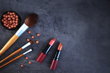 Make-up brushes, lipsticks, and blusher, on grey background