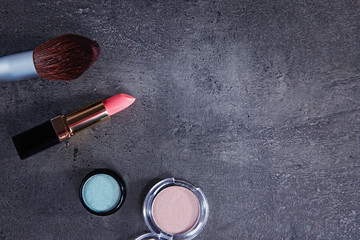 Makeup brush and cosmetics on grey background, copy space