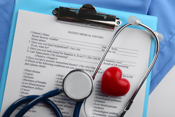 A stethoscope, coat, plastic heart and clipboard, close-up