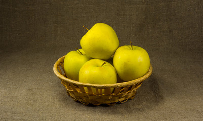 Several apples in a basket on a background of burlap