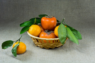 basket with tangerines and persimmons on sacking