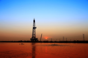 Obraz premium In the evening, the silhouette of oilfield derrick