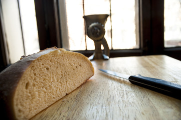 Half of sourdough loaf with knife and meat grinder on table