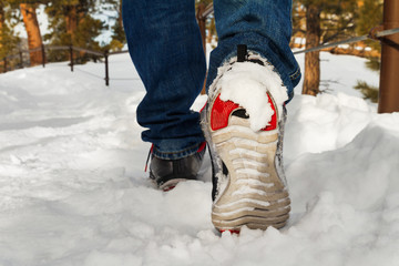 Man walking in running shoes on snow path, focus on right shoe