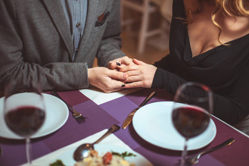 Beautiful young couple with glasses of red wine in luxury restaurant