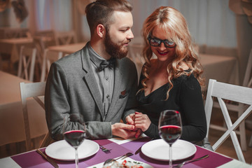 Beautiful young couple with glasses of red wine in luxury restaurant