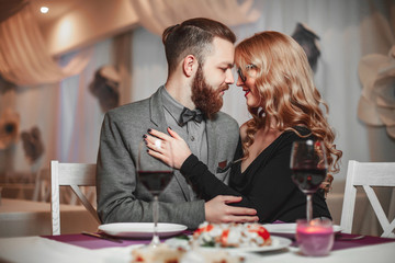 Beautiful young couple with glasses of red wine in luxury restaurant