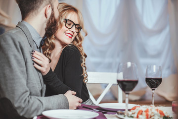 Beautiful young couple with glasses of red wine in luxury restaurant