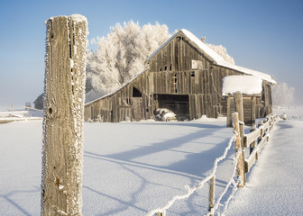 Close up of a fence post with wooden barn winter