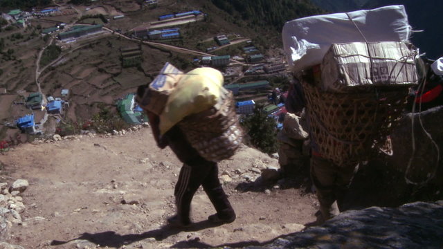 Sherpa porters walking to Namche Bazaar, Nepal carrying baskets.