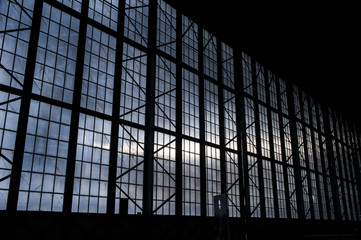 Silhouette of airplane hanger with blue clouds in background