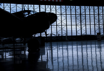 Silhouette prop airplane in hanger with rflection 