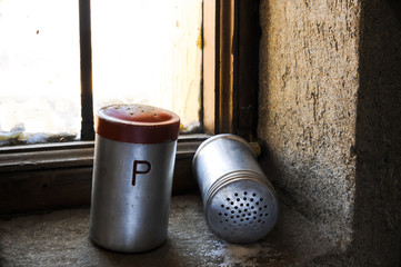 Salt and pepper shaker with red top on windowsill 