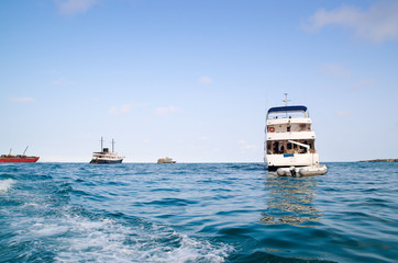 Several smaller ships outside Galapagos islands sailing on beautiful blue pacific ocean