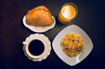 Elegant breakfast concept seen from above, coffee cup, bread, orange juice and scrambled eggs