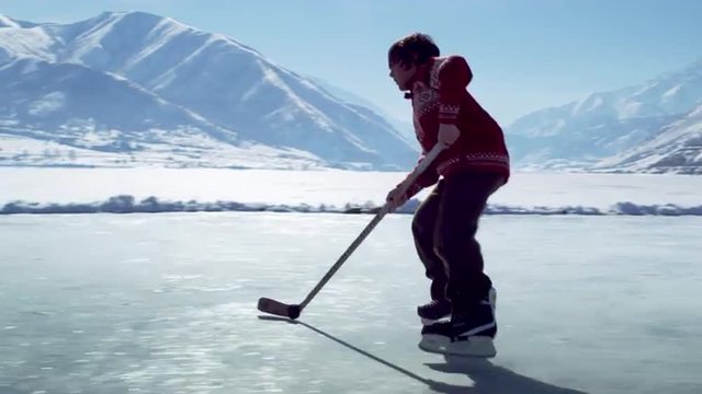 Young boy practicing hockey at an outdoor ice rink.