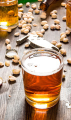 Glass of beer and pistachios on a wooden table.