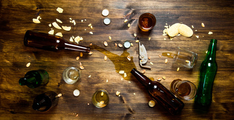 In the process of party - spilled beer, bottle caps and leftover chips on the table. - obrazy, fototapety, plakaty