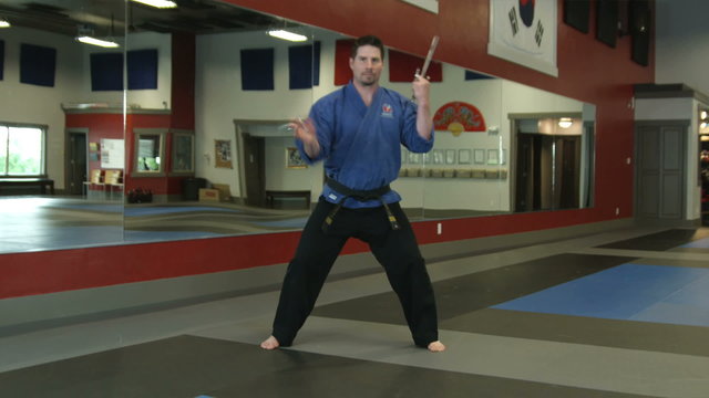 Man in karate studio practicing sai weapon moves