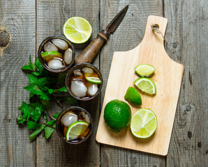 Fresh cocktail with lime and mint on wooden table.