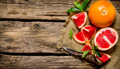 he grapefruit cut on the old fabric with leaves and knife.