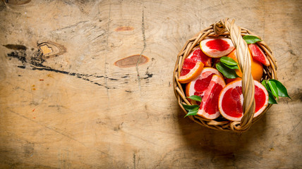 Fresh sliced grapefruit in a basket. On wooden table.