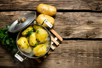 Boiled potatoes with herbs on wooden table . Free space for text.
