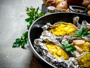 Baked potatoes in a pan on an old rustic table .