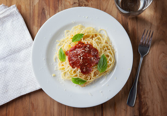 spaghetti with tomato sauce in plate on wooden board