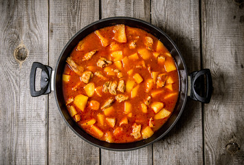 Stewed potatoes with meat and spices on a wooden table .