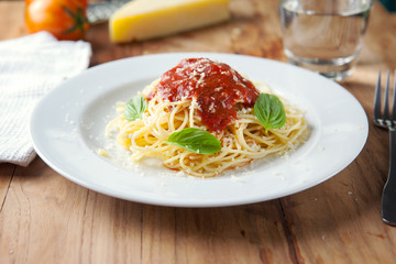 spaghetti with tomato sauce in plate on wooden board